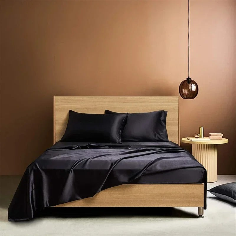 Bed with black satin bedding and pillows against a brown wall.