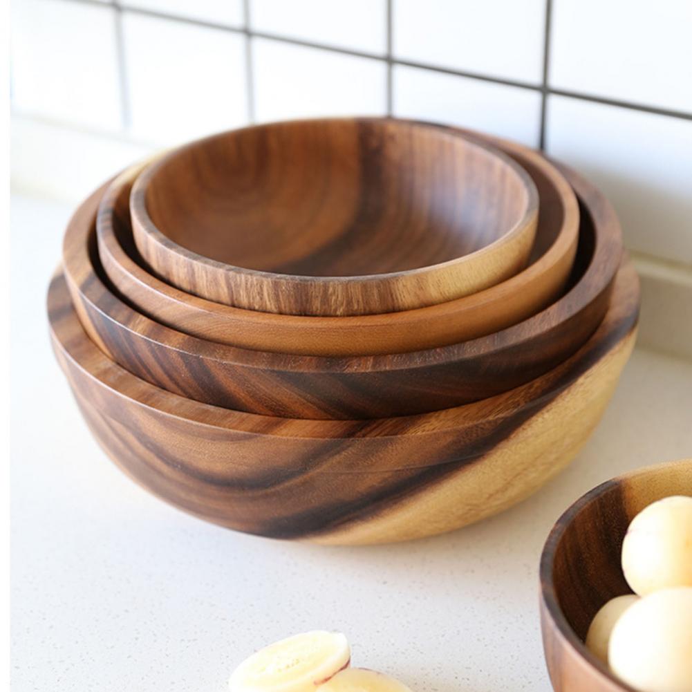 Stack of wooden bowls on a light surface with a tiled wall background