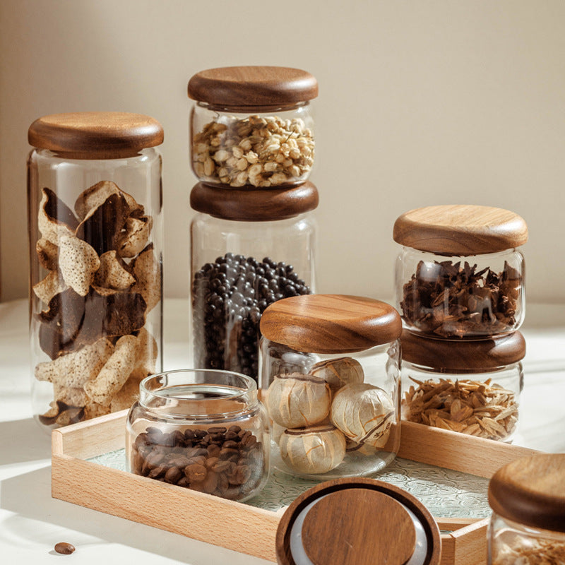 Set of glass jars with wooden lids containing various spices on a light surface.