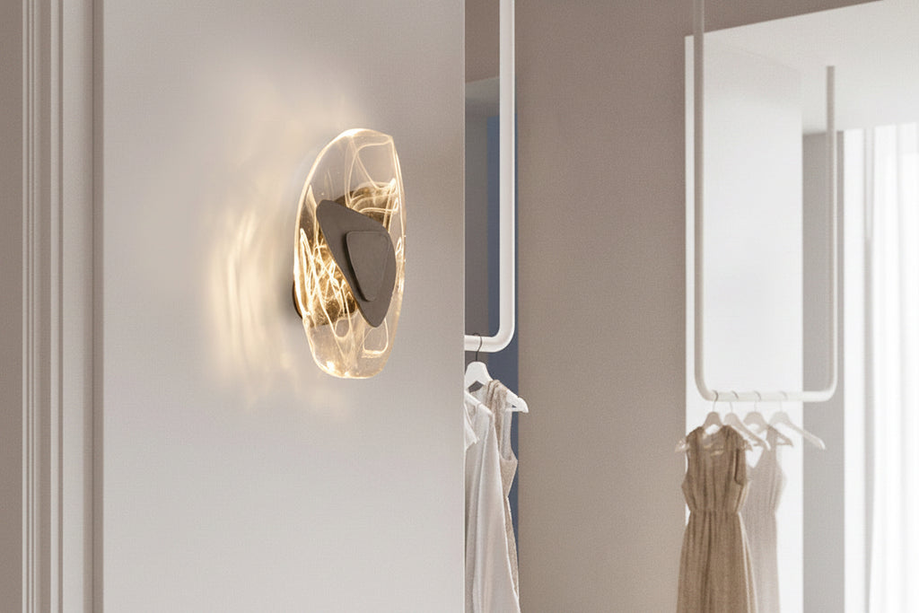 Wall-mounted light fixture in a room with shoes and clothing on hangers.