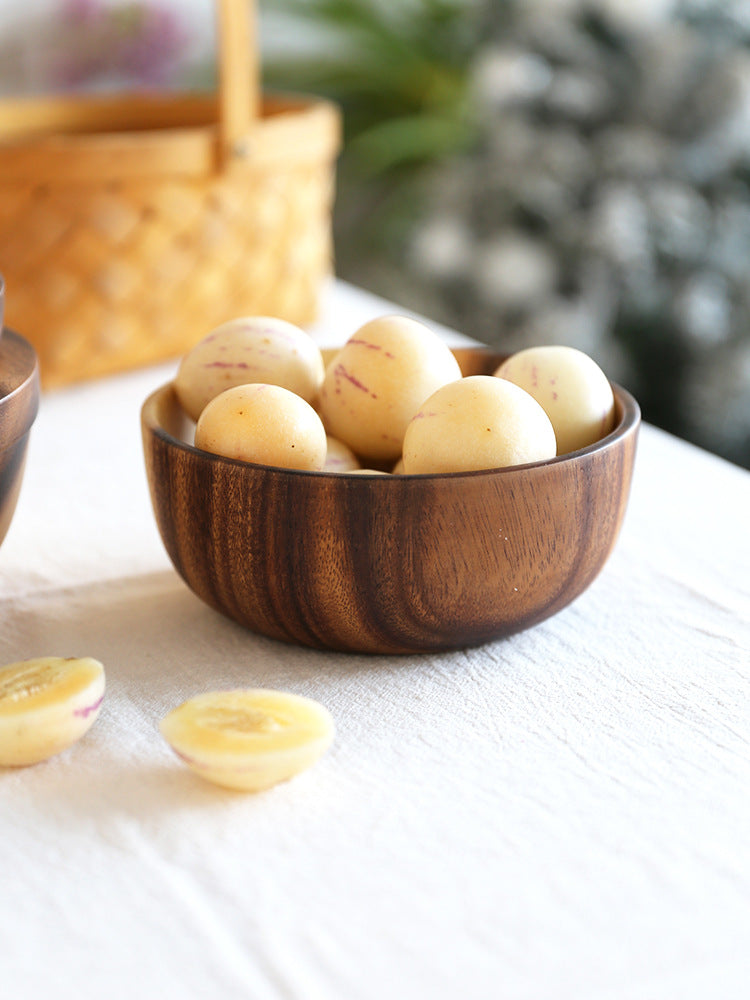 Wooden bowl filled with potatoes on a white surface