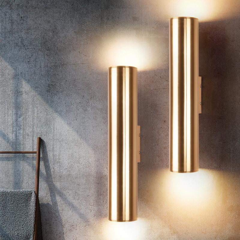 Two gold cylindrical wall lights on a textured wall.