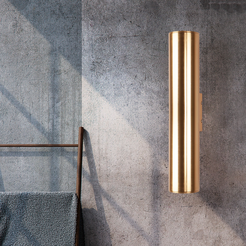 Gold cylindrical wall sconce on a textured gray wall