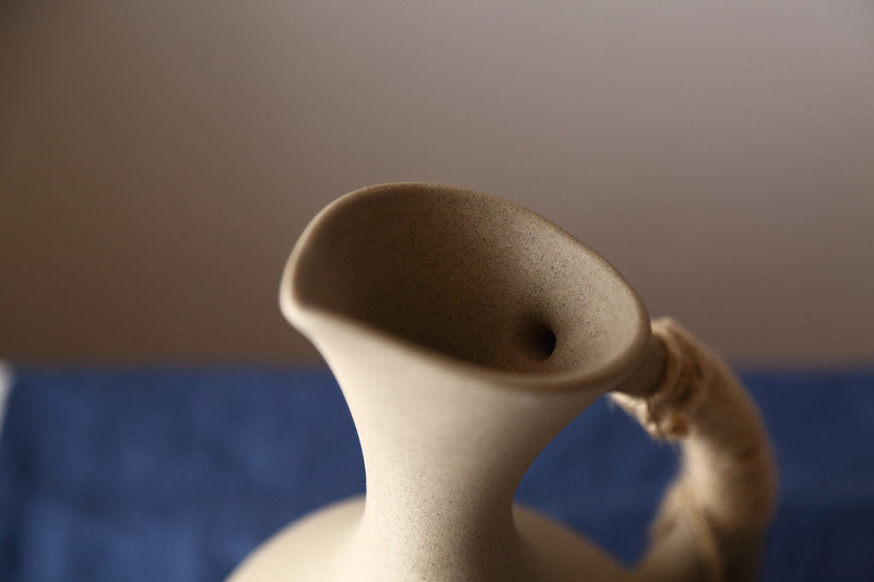 Ceramic pitcher on a blue surface with a neutral background