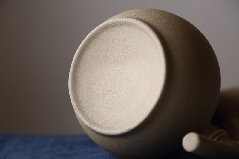 Close-up of a ceramic teapot with a textured beige lid on a blurred background