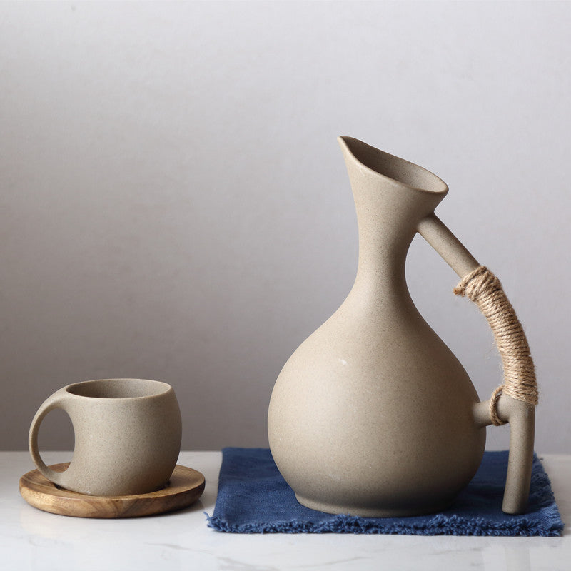 Ceramic pitcher and mug on a white surface with a gray background