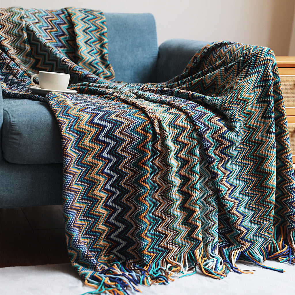 Patterned blanket draped over a blue armchair with a cup on a small table.