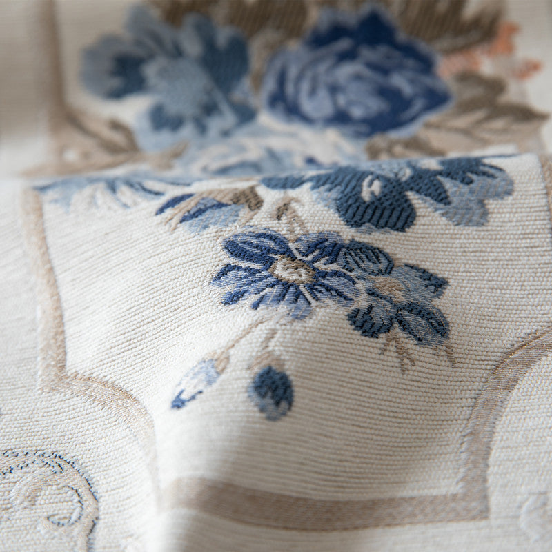 Close-up of a floral embroidered fabric with blue flowers on a beige background