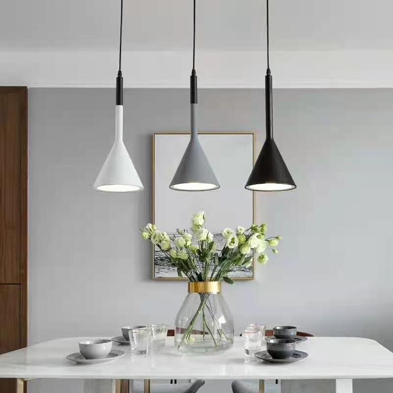 Modern dining room with pendant lights and a vase of flowers on the table.