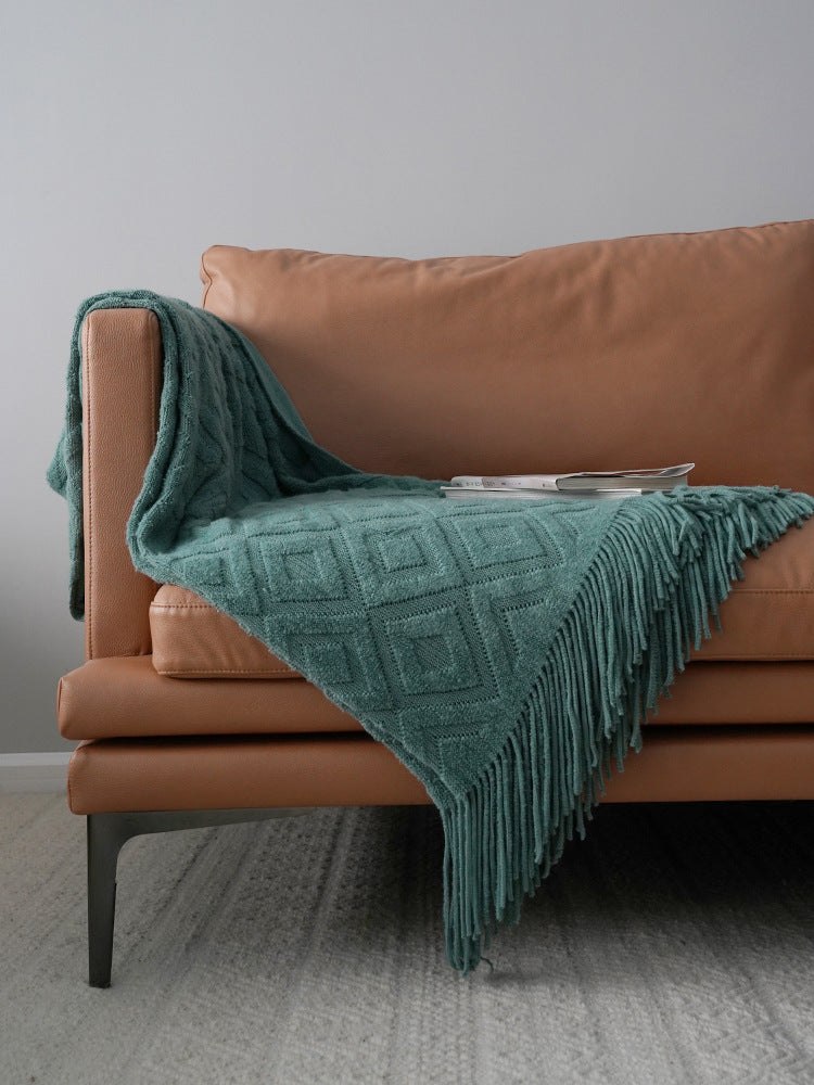Teal blanket draped over a brown sofa against a gray wall.