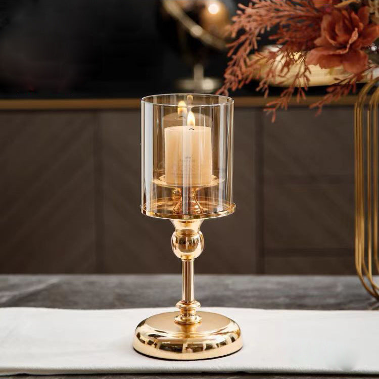Gold candle holder with a lit candle on a table
