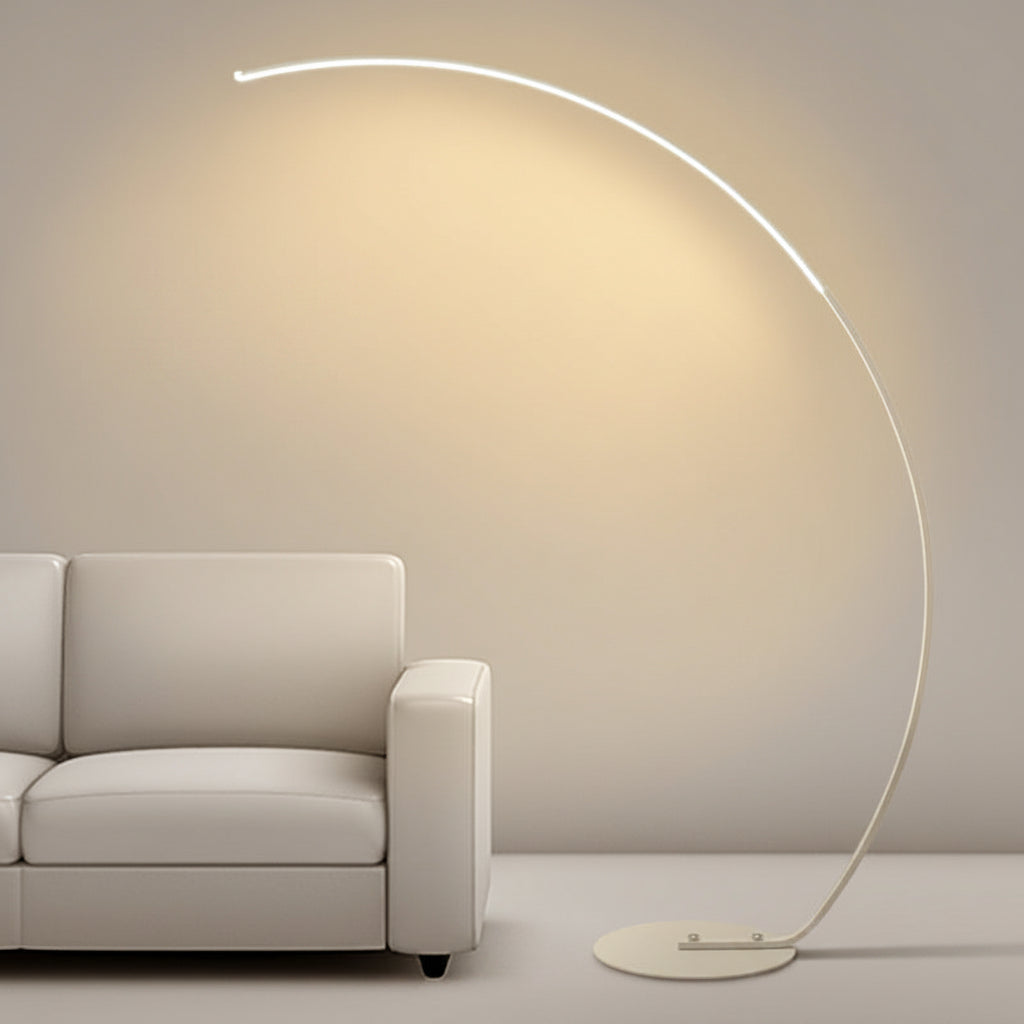 Modern floor lamp with a curved design next to a sofa in a minimalistic room.