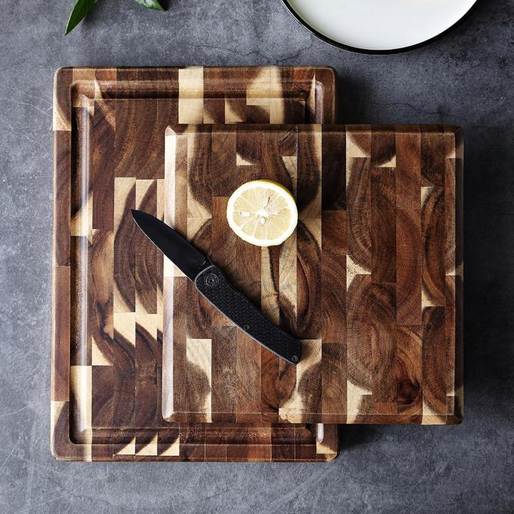 Wooden cutting board with geometric pattern, knife, and lemon slice on a dark surface