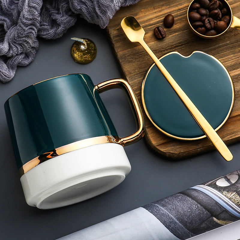 Teal mug with gold accents on a dark surface with a wooden tray and coffee beans.