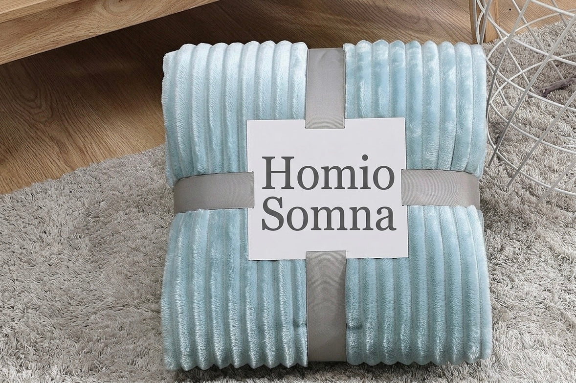 Folded light blue blanket with 'Homio Somna' label on a textured surface