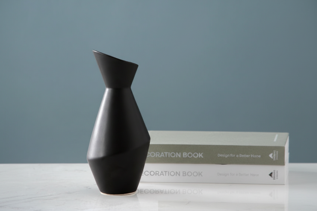 Black ceramic vase on a white surface with a gray background