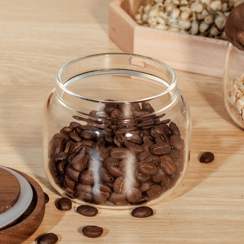 Glass jar filled with coffee beans on a wooden surface