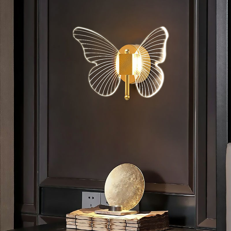 Butterfly-shaped wall light fixture on a dark wall with a decorative object below.