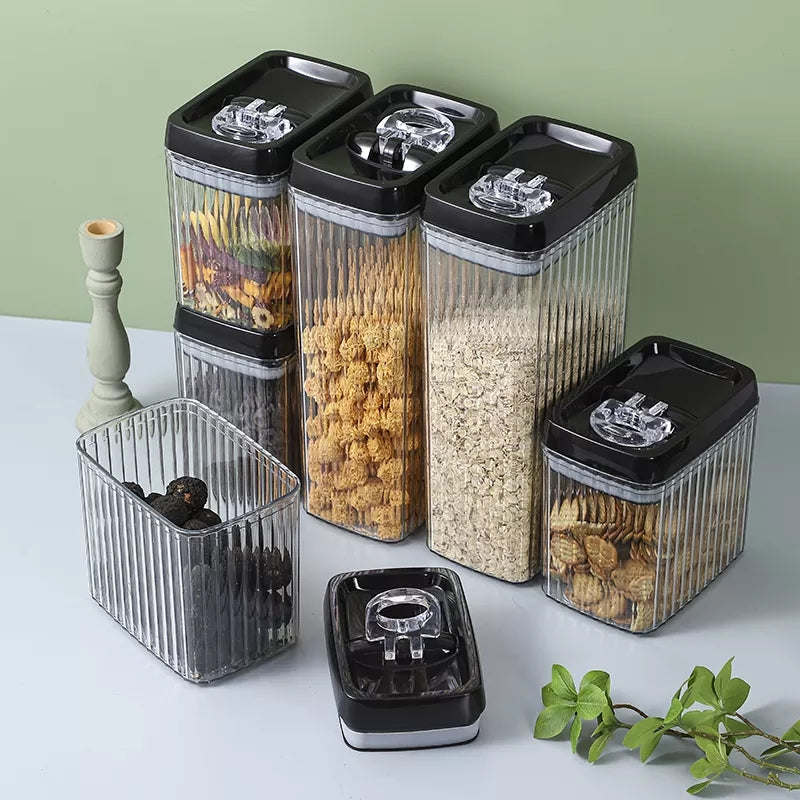 Set of clear storage containers with black lids on a light surface.