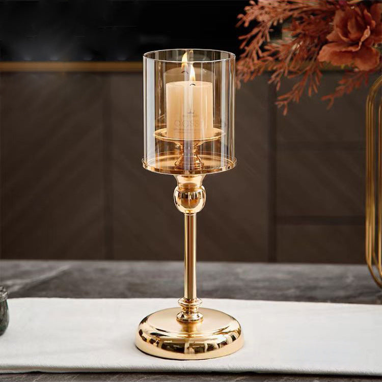 Gold candle holder with a lit candle on a marble surface