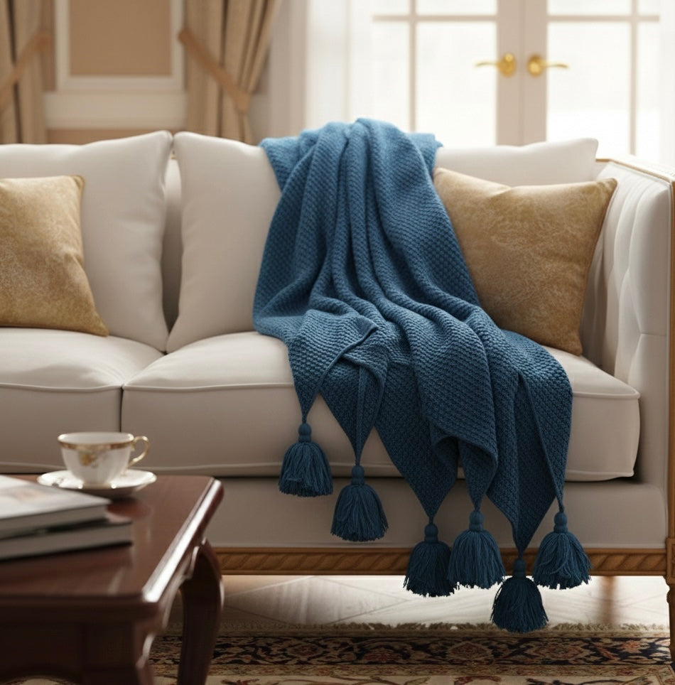 White sofa with a blue blanket and gold pillows in a living room setting.