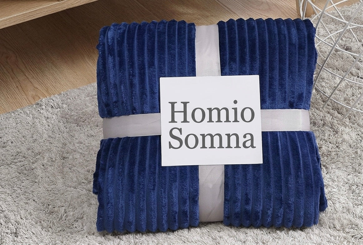 Folded blue blanket with 'Homio Somna' label on a gray rug