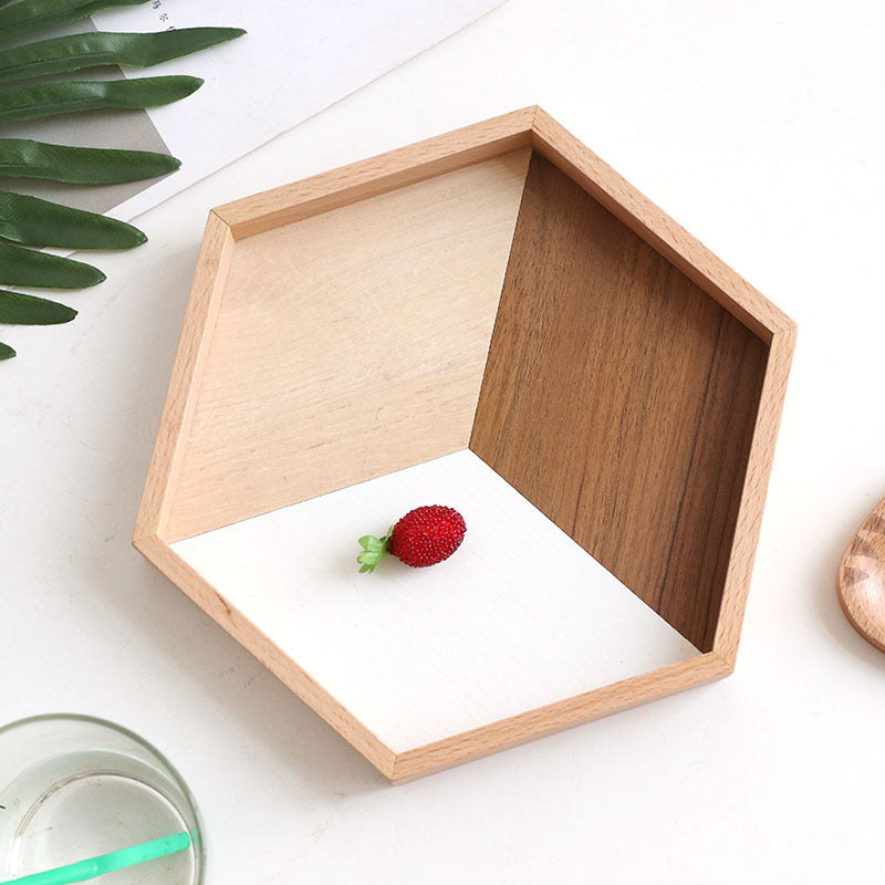 Hexagonal wooden tray with a red berry on a white surface