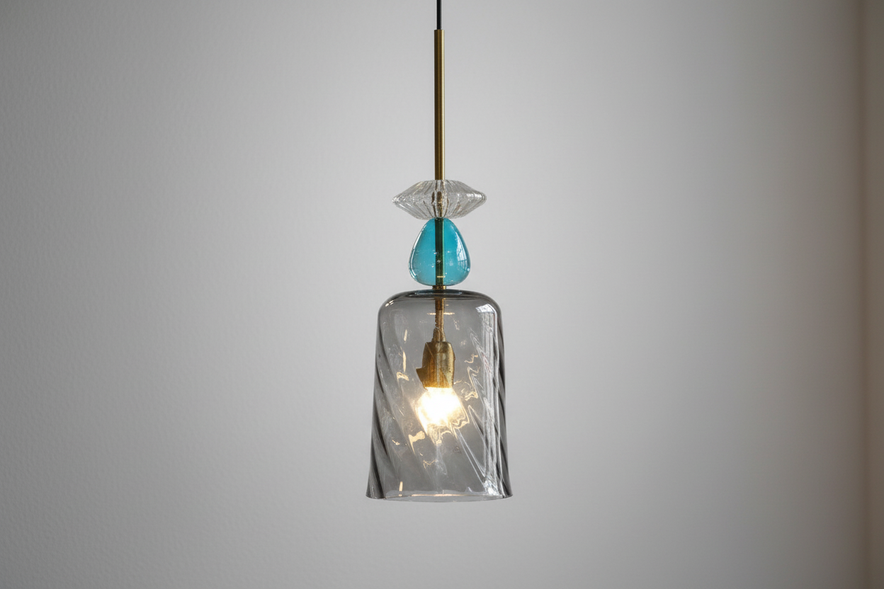 Pendant light with clear glass shade and turquoise accent on a gray background