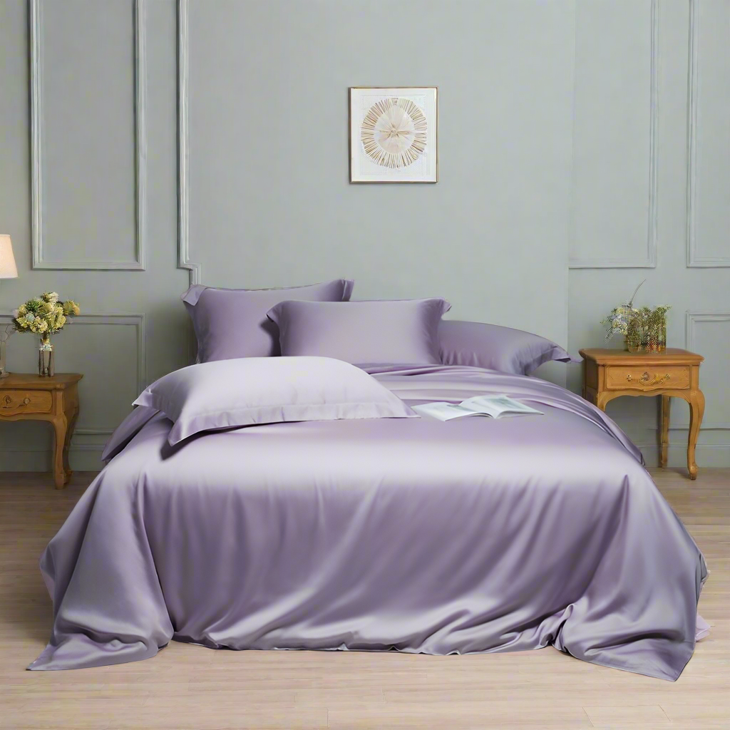 Purple bedding set on a bed in a bedroom with light gray walls and wooden furniture.
