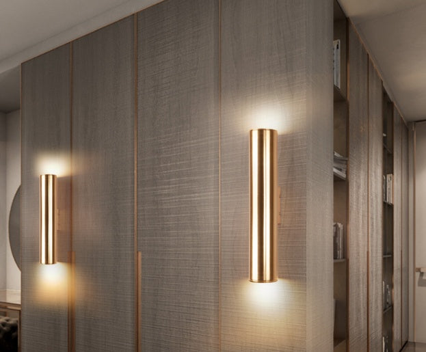 Two gold wall sconces on a textured wall in an indoor setting.