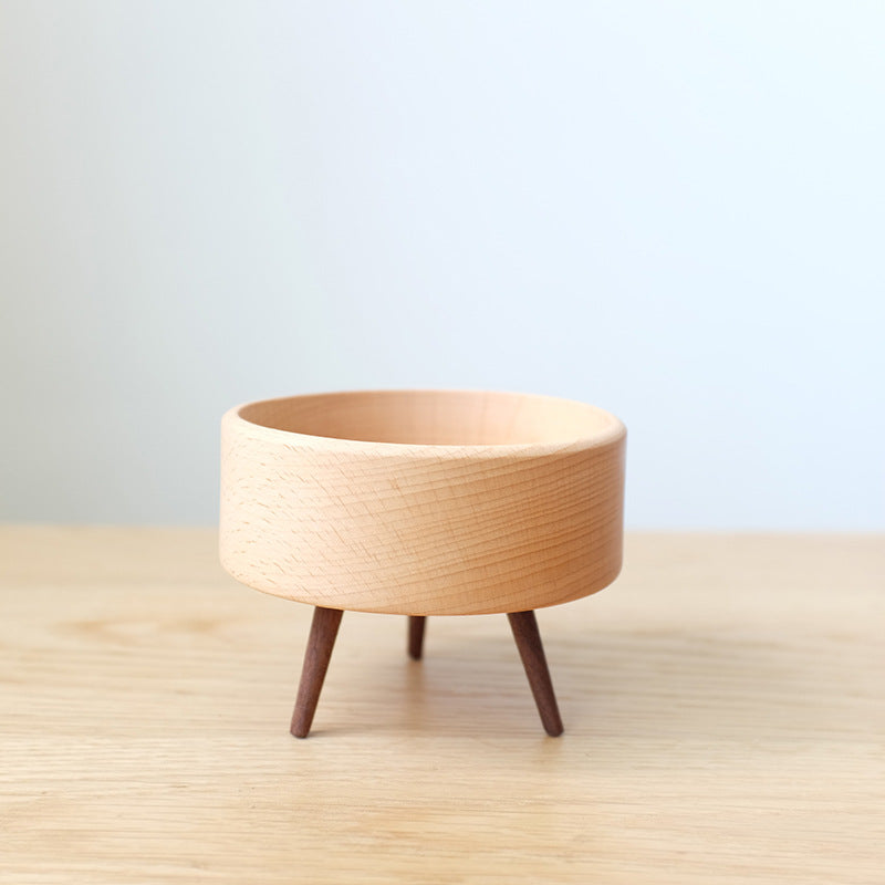 Wooden planter with legs on a light wooden surface and light blue background