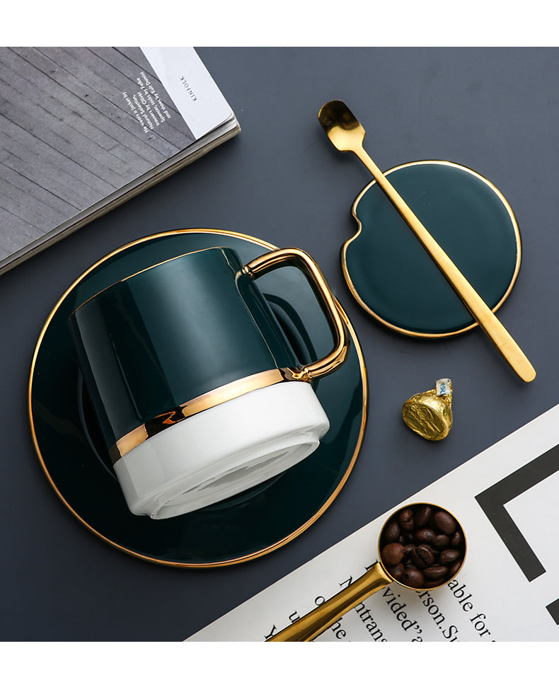 Green mug with gold accents on a dark surface with a spoon and coffee beans.
