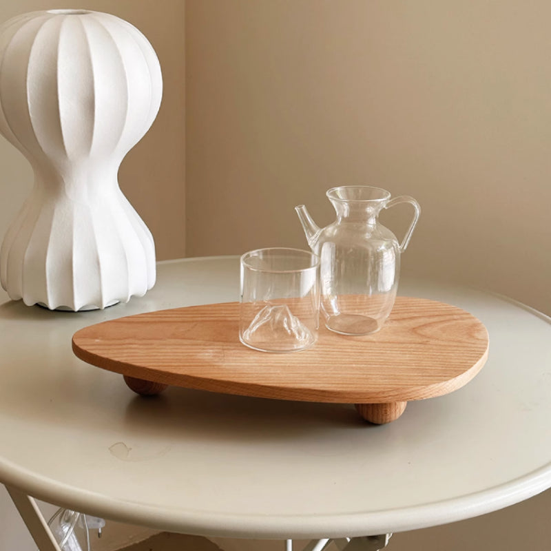 Wooden tray with glassware on a round table against a beige wall