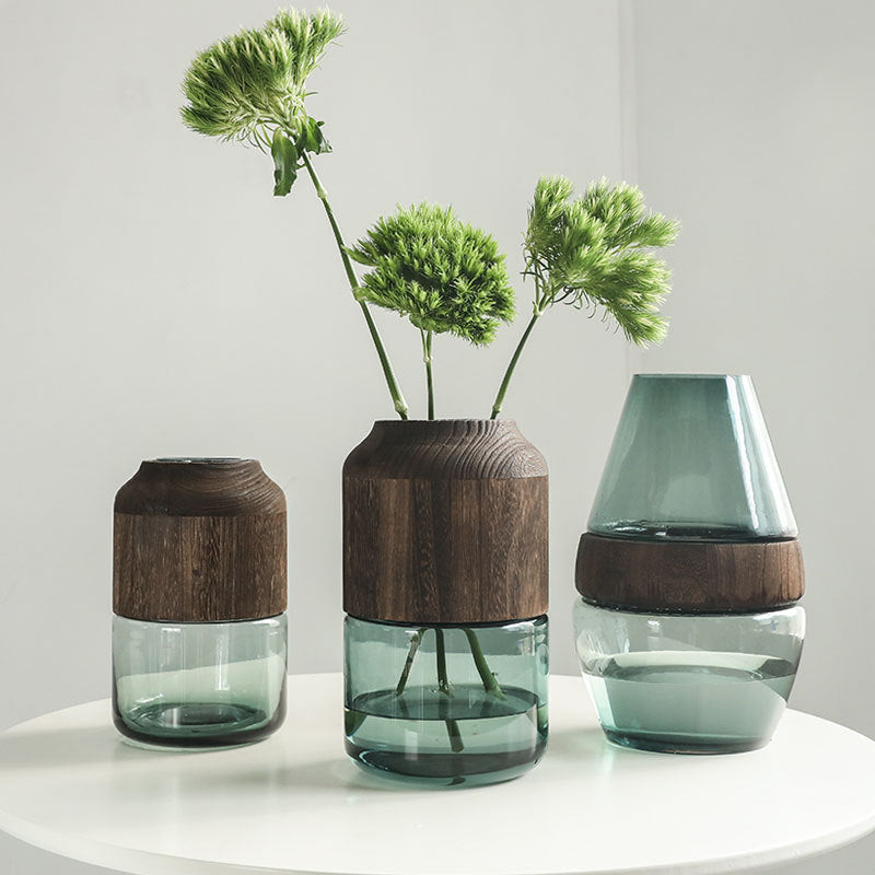Three glass vases with wooden tops on a white surface against a light gray background