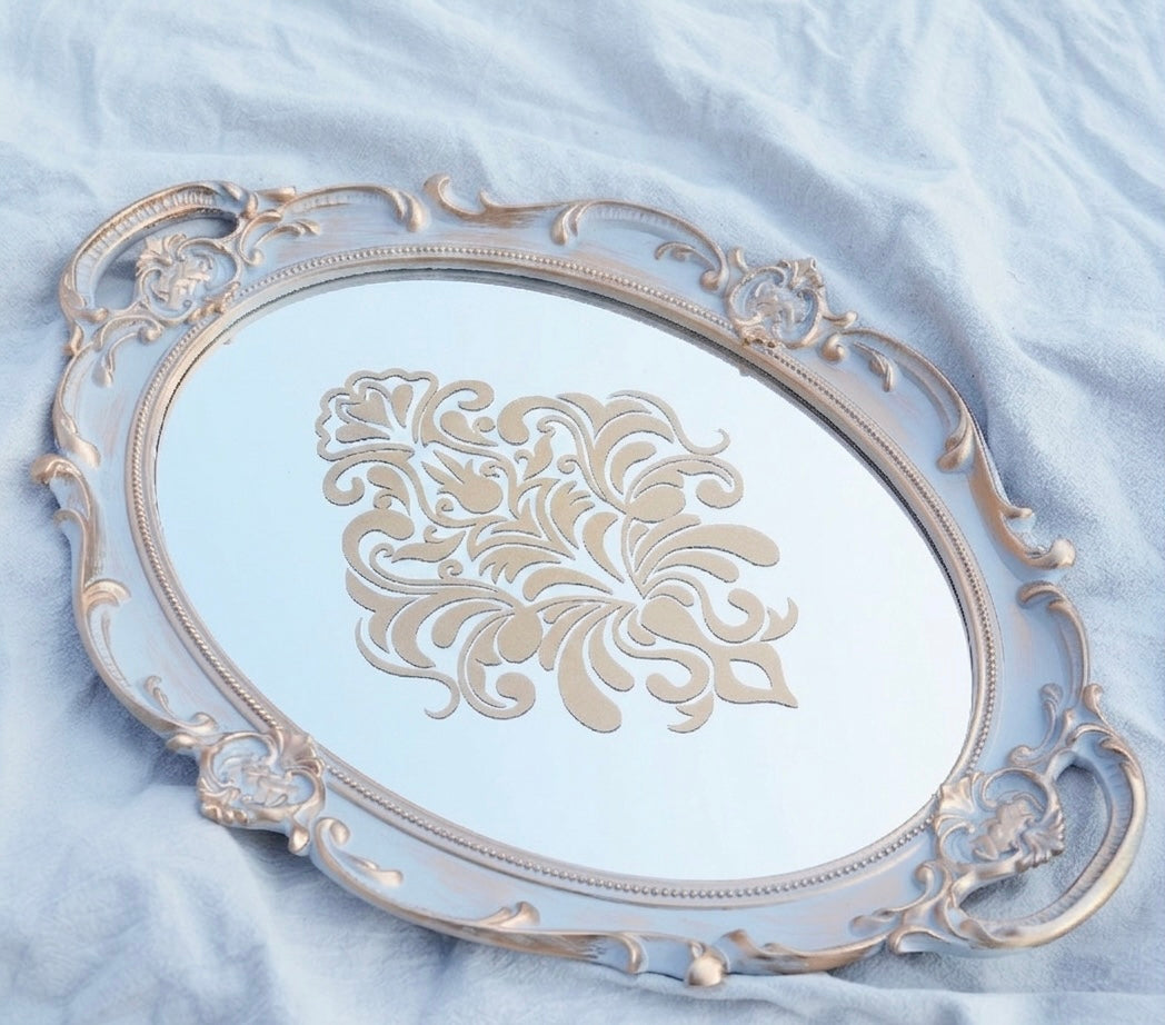 Decorative silver tray with intricate designs on a light blue fabric background