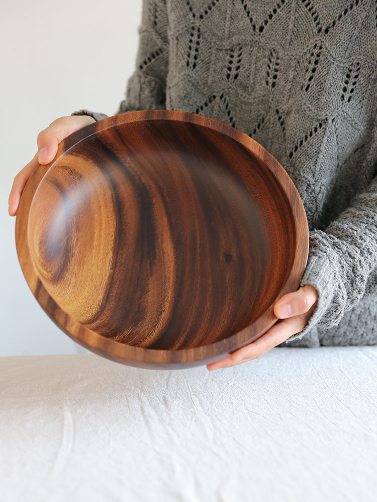 Person holding a wooden bowl with a plain background