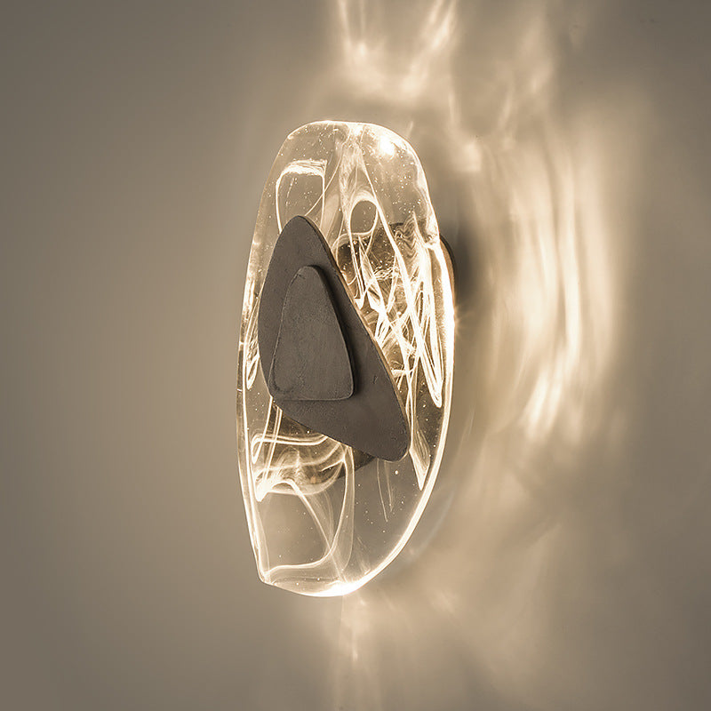 Wall-mounted light fixture with a glass cover and dark accent on a neutral background