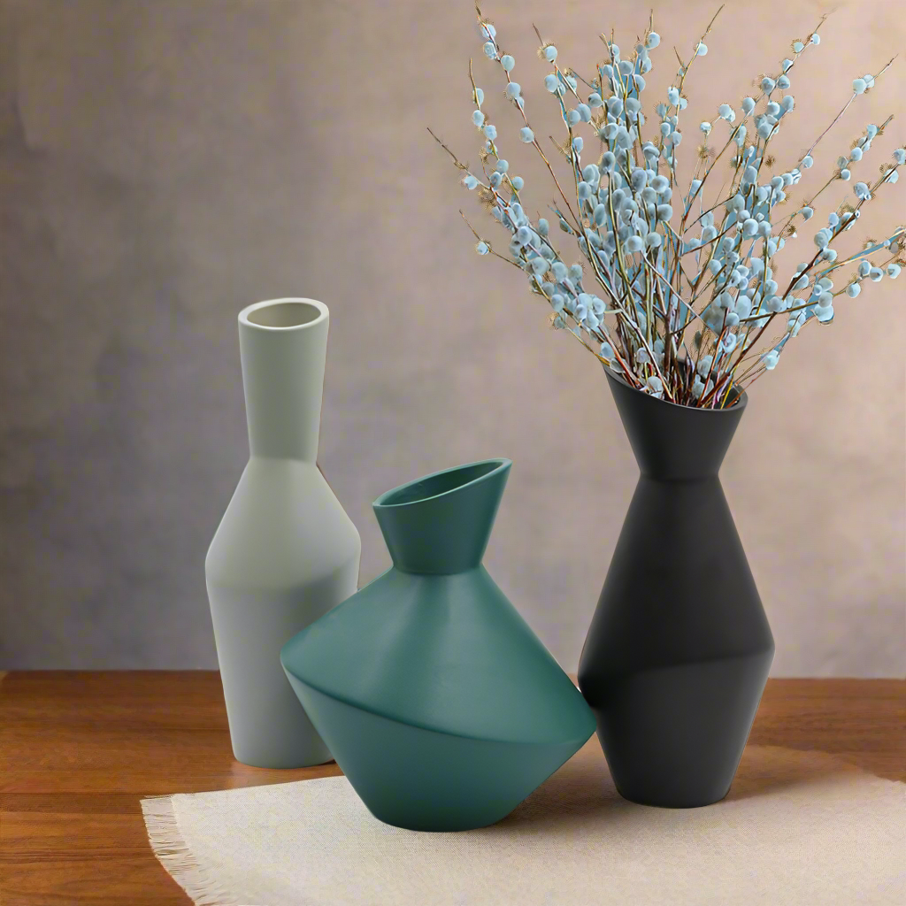 Three ceramic vases of different shapes and colors on a wooden surface with a neutral background