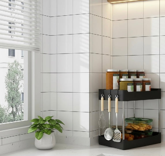 Black wall-mounted kitchen organizer with utensils and containers against a tiled wall.