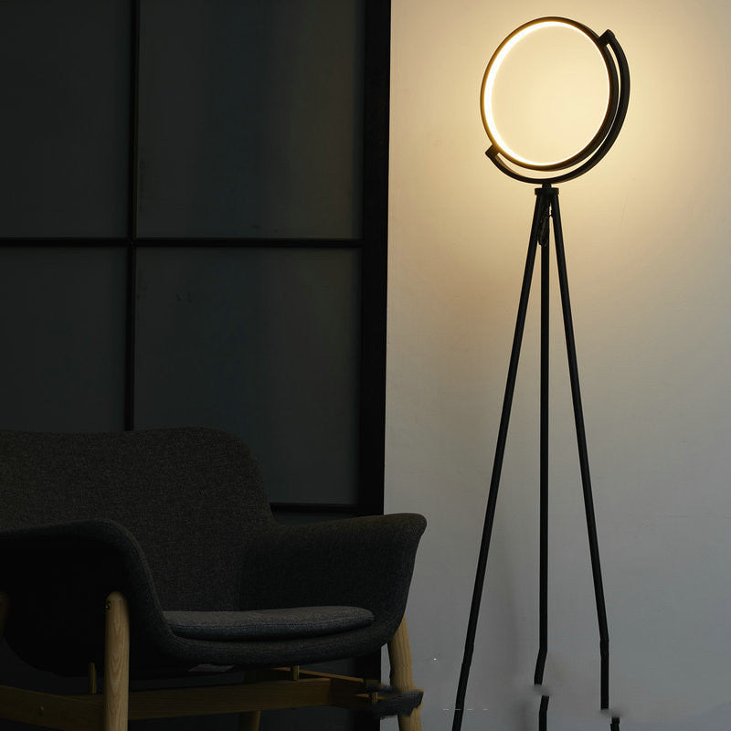 Modern floor lamp with a circular design in a dimly lit room.