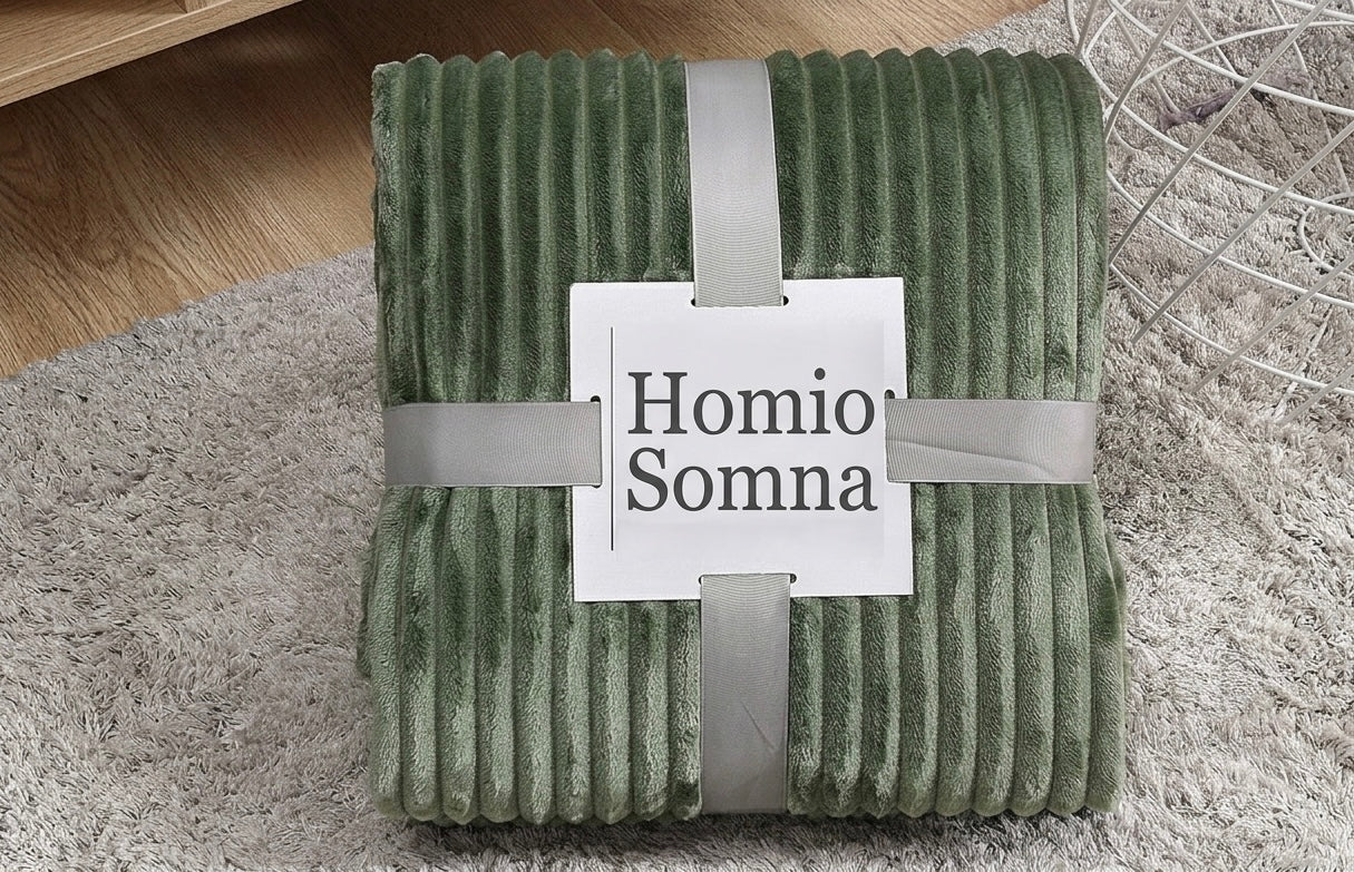 Green textured blanket with 'Homio Somna' label on a carpeted floor