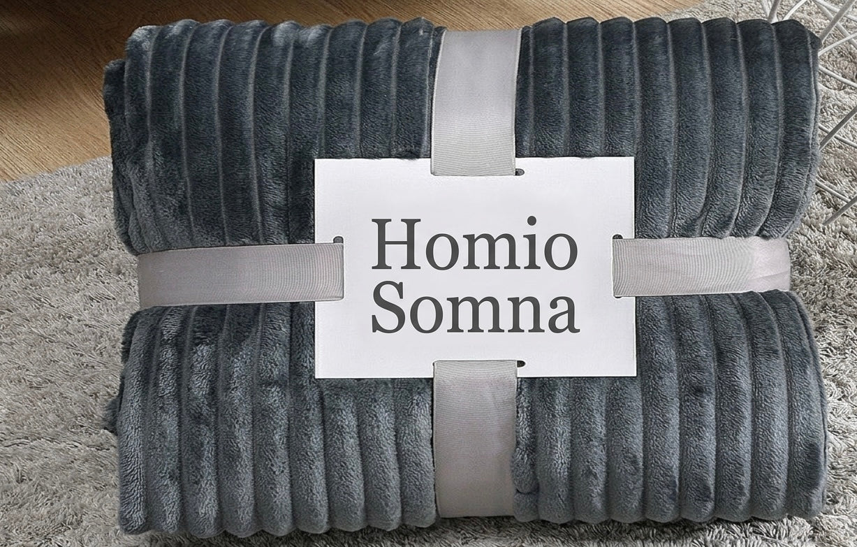 Folded gray blanket with 'Homio Somna' label on a textured surface