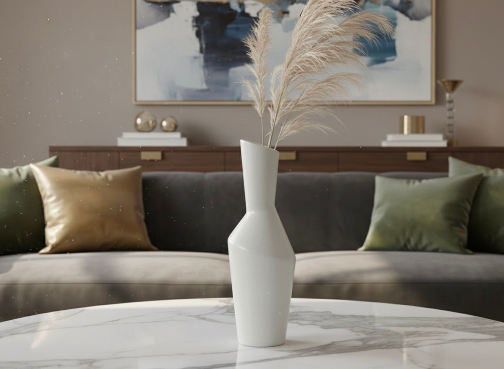 White vase with dried plants on a marble table in a living room setting.