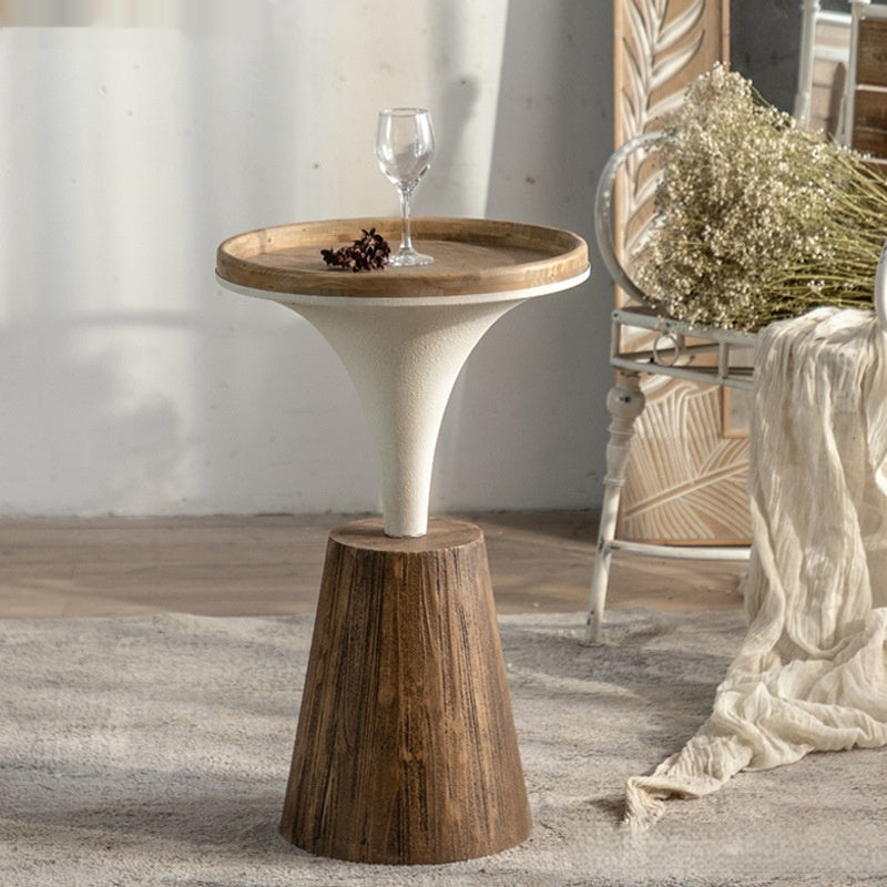 Small wooden side table with a glass of wine and a decorative item in a home setting.