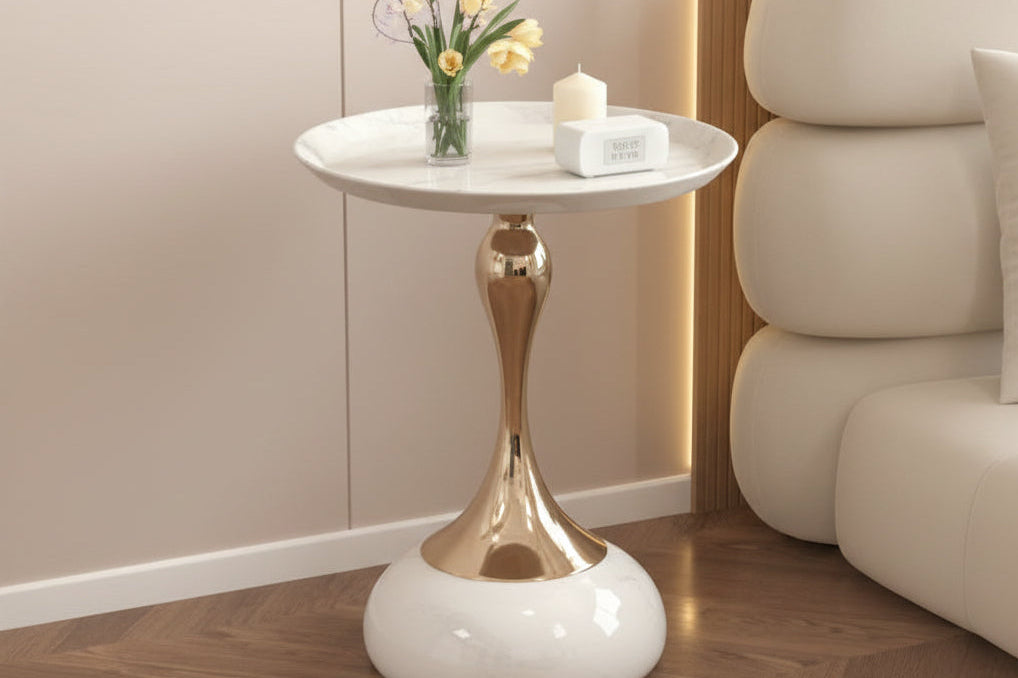 Modern side table with gold base and white top in a living room setting.