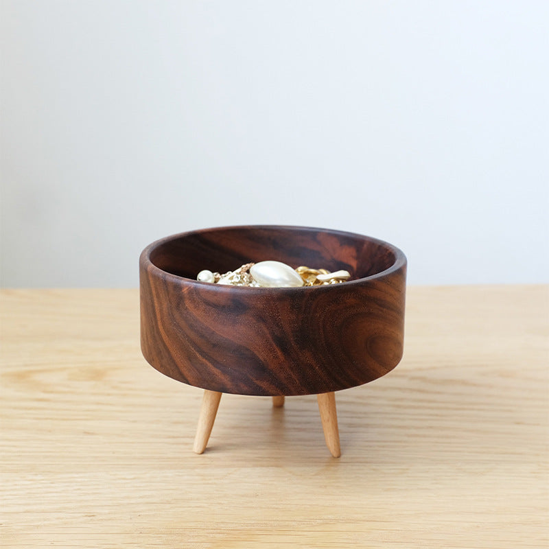 Wooden bowl with legs on a light wooden surface