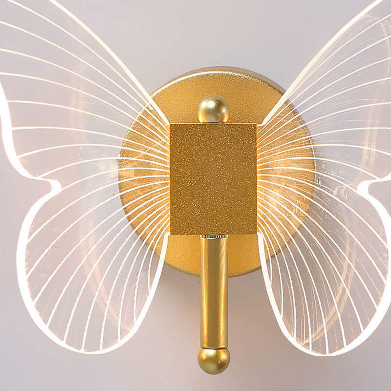 Gold wall sconce with butterfly wings on a light gray background