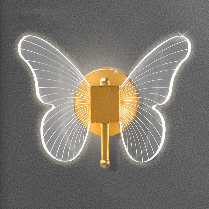 Butterfly-shaped wall light with gold center and transparent wings on a dark background