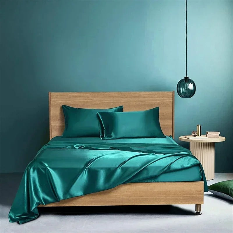 Teal satin bedding set on a wooden bed against a teal wall.