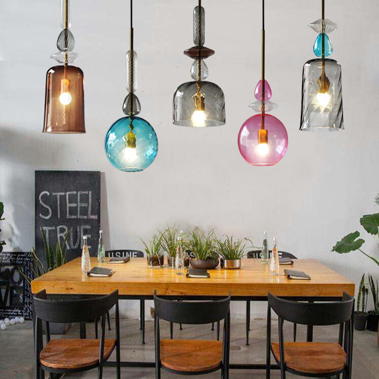 Colorful pendant lights hanging above a wooden dining table with black chairs.